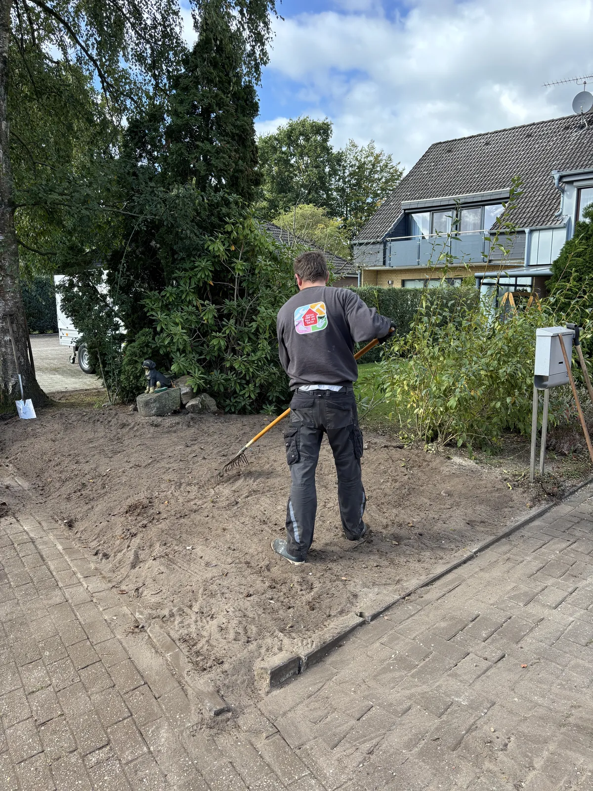 Mitarbeiter harkt eine freie Bodenfläche im Garten